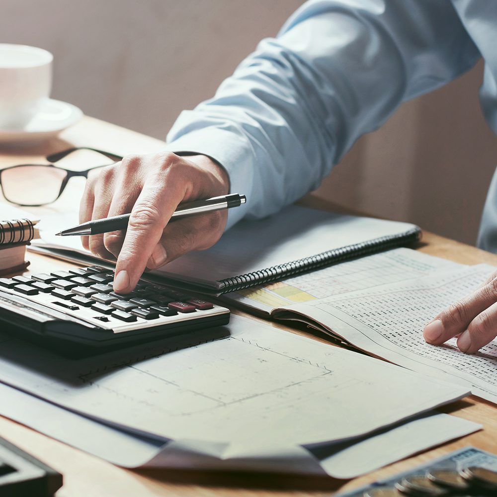 businessman working on desk office with using a calculator to calculate the numbers, finance accounting concept