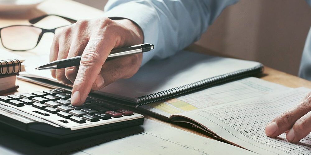 businessman working on desk office with using a calculator to calculate the numbers, finance accounting concept